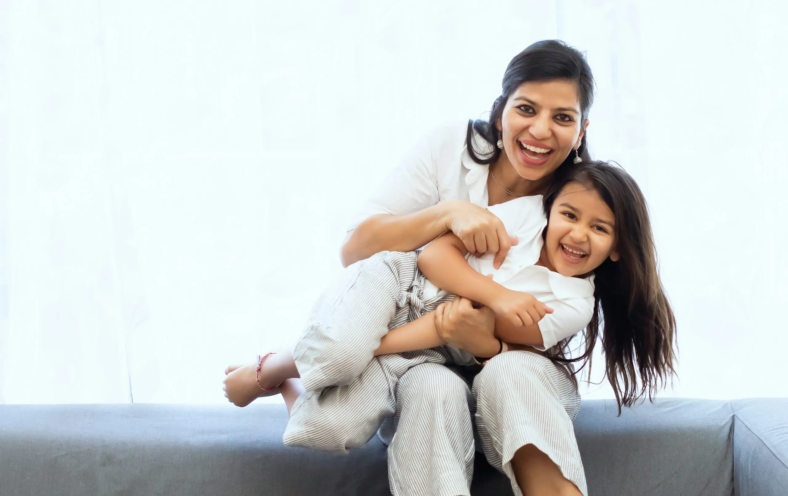 A mother and daughter laughing together on a sofa
